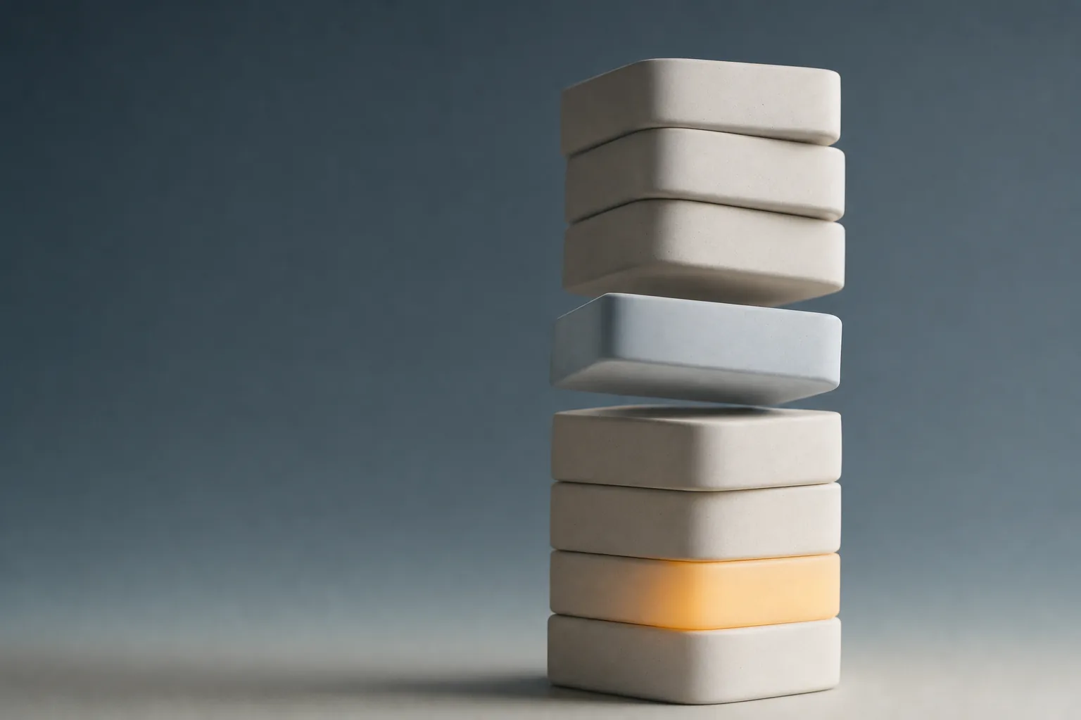 A stack of smooth matte blocks with one block lifted out of the middle, leaving the blocks above it out of alignment